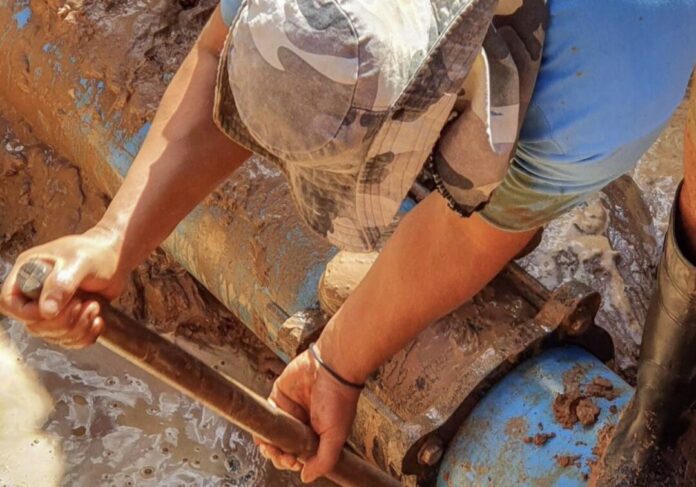 Homem consertando cano em lama