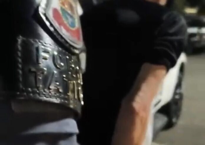 Pessoa com uniforme e carro ao fundo
