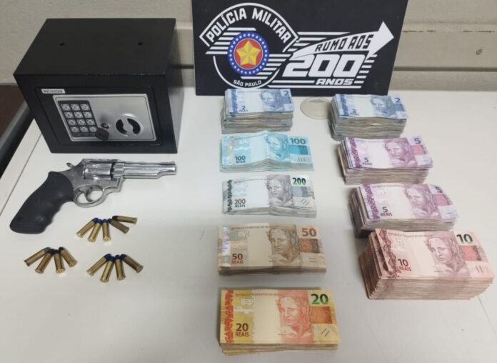 Dinheiro, arma e cofre na mesa.