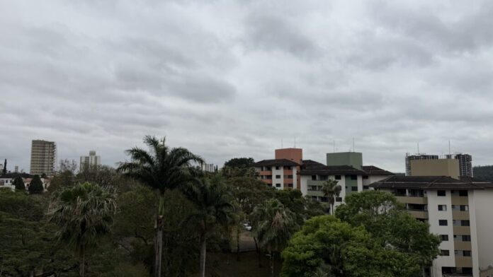 Céu nublado sobre prédios e árvores.