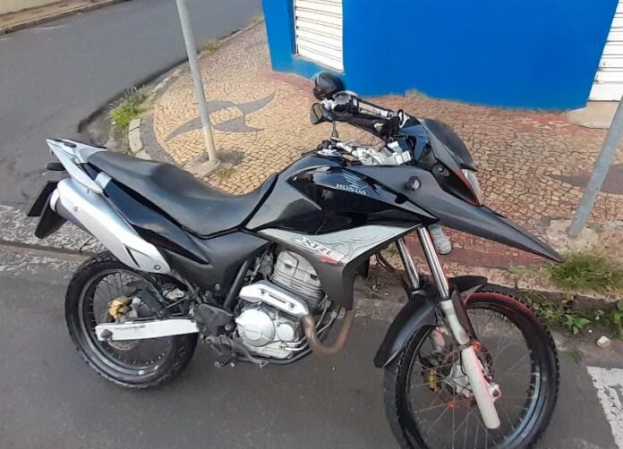Moto preta estacionada na calçada.