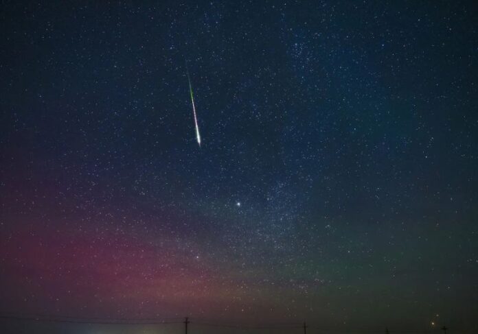 Céu estrelado com meteoro brilhante.